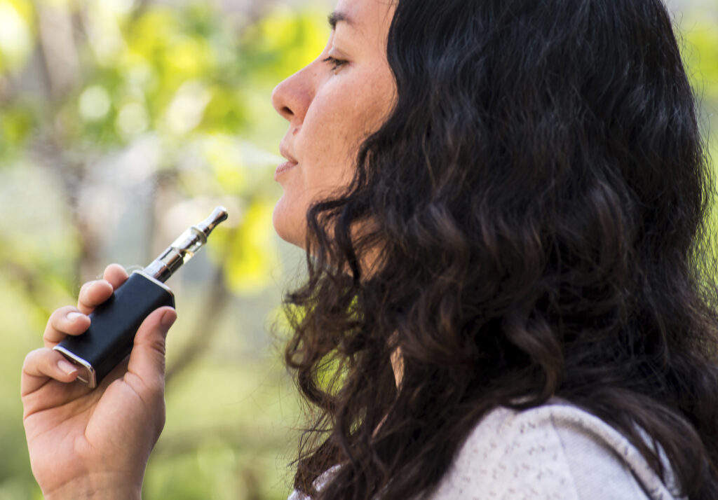 Kvinde bruger en e-cigaret udendørs